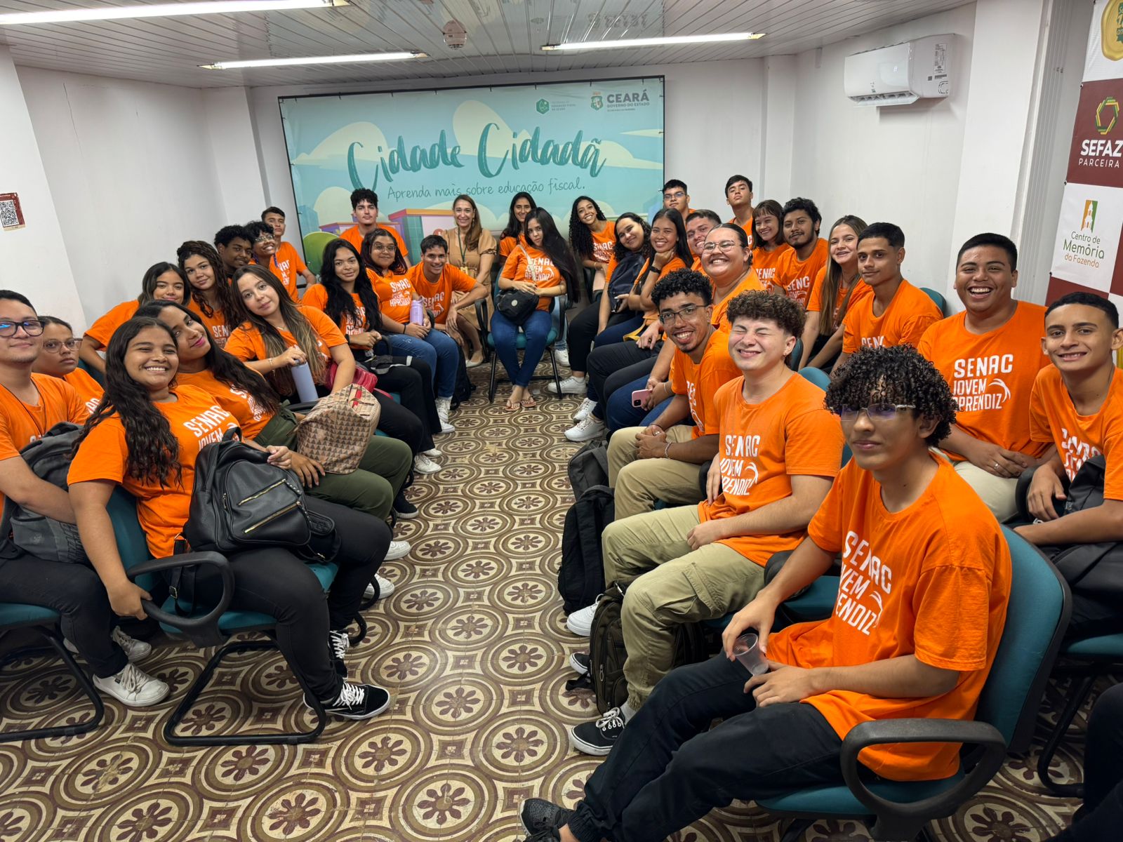 Visita do grupo de 35 alunos do curso de Assistente Administrativo do Senac, acompanhados pelo professor Ismael, na tarde do dia 11 de fevereiro de 2025. Esse encontro fez parte das atividades educativas promovidas pelo Centro de Memória da Fazenda, com foco em temas relacionados à gestão pública e educação fiscal. Foto: Estudantes na Sala Multiuso do Centro de Memória da Fazenda.