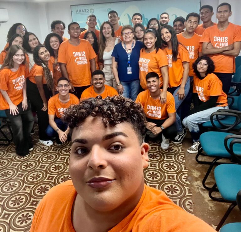 Foto de um grande grupo de estudantes do Senac e a professora Glória, posando para uma selfie durante uma visita.
