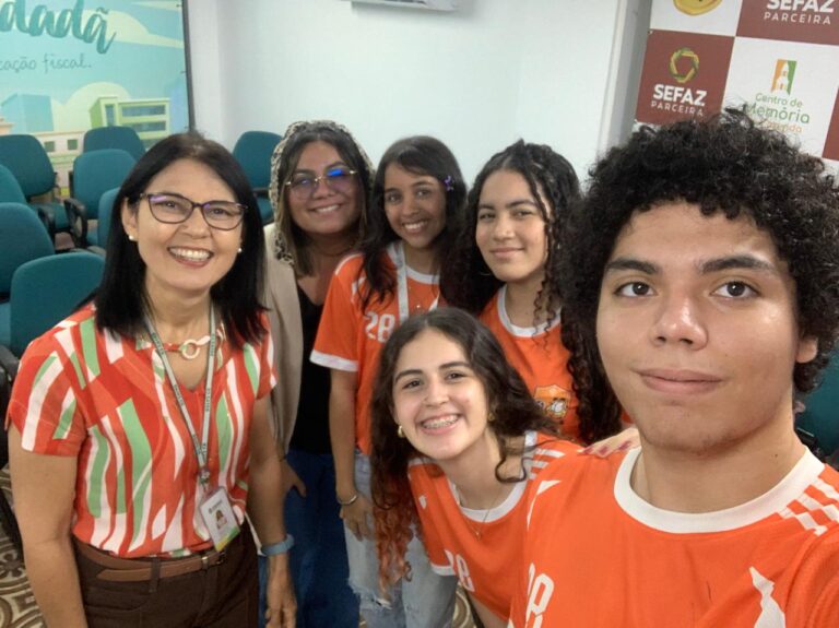 Seis alunos e a professora Jessyca Anne Lemos do EEMTI Visconde do Rio Branco, posando juntos durante um evento da SEFAZ.