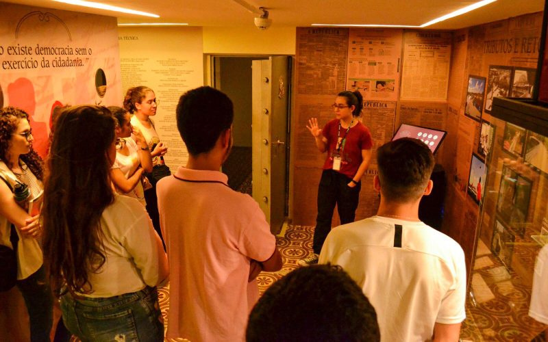 Visita do grupo de estudantes da turma de contabilidade financeira da Universidade de Fortaleza (Unifor), acompanhada pelo professor Paulo Henrique Vieira Gomes, no dia 15 de Junho. As visitas fazem parte do projeto Escola no Fisco, idealizado pelo Programa de Educação Fiscal (PEF-CE), com o objetivo de convidar estudantes para conhecerem as atividades desenvolvidas pela Secretaria da Fazenda do Ceará (Sefaz-CE) e refletirem sobre tributação e cidadania. Foto: estudantes na exposição “Notas de Memória” do Centro de Memória da Secretaria da Fazenda do Ceará.