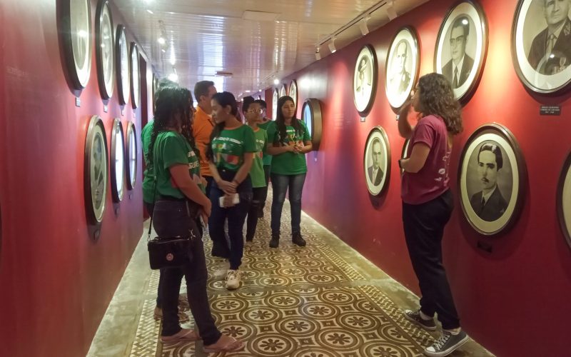 Visita do grupo de estudantes do Projeto Virando o Jogo, iniciativa do Governo do Estado do Ceará em parceria com o Serviço Nacional de Aprendizagem Comercial (Senac) Ceará, no dia 20 de Junho. As visitas fazem parte do projeto Escola no Fisco, idealizado pelo Programa de Educação Fiscal (PEF-CE), com o objetivo de convidar estudantes para conhecerem as atividades desenvolvidas pela Secretaria da Fazenda do Ceará (Sefaz-CE) e refletirem sobre tributação e cidadania. Foto: estudantes na exposição Galeria do Secretários do Centro de Memória da Secretaria da Fazenda do Ceará.