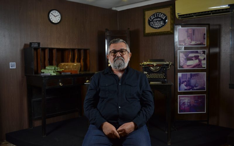 Visita de Argemiro Torres, servidor fazendário e um dos primeiros gestores da Educação Fiscal da Secretaria da Fazenda. Na ocasião, o servidor foi convidado a registrar em vídeo o seu depoimento sobre sua experiência com os programas de promoção à Educação Fiscal. Foto: Argemiro Torres durante a gravação de seu depoimento, realizada na exposição Notas de Memórias do Centro de Memória da Fazenda.