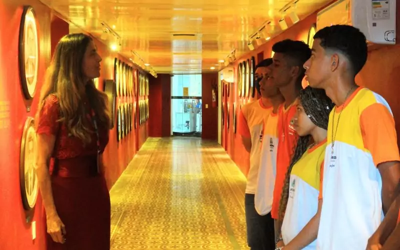 Durante a visita os alunos conheceram mais sobre o funcionamento da Secretaria da Fazenda e sobre como as mudanças sociais  históricas influenciaram a dinâmica do Fisco no Ceará. Os estudantes foram acolhidos por Clarissa Barroso, supervisora do Núcleo de Cidadania Fiscal e gestora do Centro de Memória da Fazenda.  Fotos: Clarissa Barroso e os alunos na Exposição Galeria dos Secretários do Centro de Memória da Fazenda. Crédito da imagem: Joziane Pontes.
