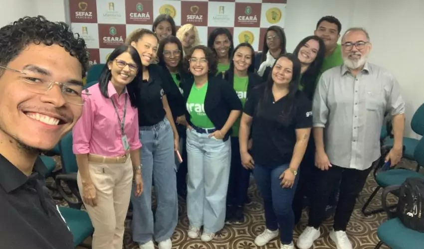 Estudantes com professores em pé na sala de multiuso da SEFAZ