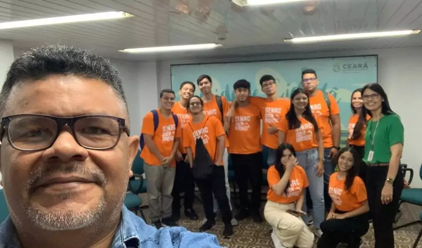 Estudantes com professor em pé na sala de multiuso da SEFAZ