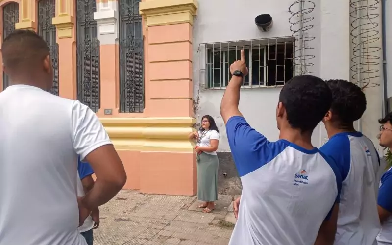 Visita do grupo de estudantes do Serviço Nacional de Aprendizagem Comercial (Senac) Ceará, no dia 30 de Junho. As visitas fazem parte do projeto Escola no Fisco, idealizado pelo Programa de Educação Fiscal (PEF-CE), com o objetivo de convidar estudantes para conhecerem as atividades desenvolvidas pela Secretaria da Fazenda do Ceará (Sefaz-CE) e refletirem sobre tributação e cidadania. Foto: estudantes no momento da visita a “Janela Testemunho” na fachada do Centro de Memória da Secretaria da Fazenda do Ceará.