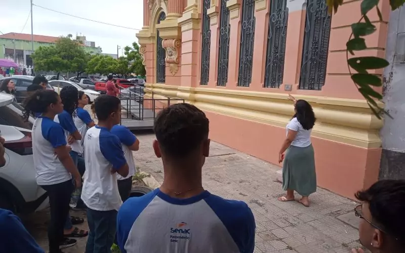Visita do grupo de estudantes do Serviço Nacional de Aprendizagem Comercial (Senac) Ceará, no dia 30 de Junho. As visitas fazem parte do projeto Escola no Fisco, idealizado pelo Programa de Educação Fiscal (PEF-CE), com o objetivo de convidar estudantes para conhecerem as atividades desenvolvidas pela Secretaria da Fazenda do Ceará (Sefaz-CE) e refletirem sobre tributação e cidadania. Foto: estudantes no momento da visita a “Janela Testemunho” na fachada do Centro de Memória da Secretaria da Fazenda do Ceará.